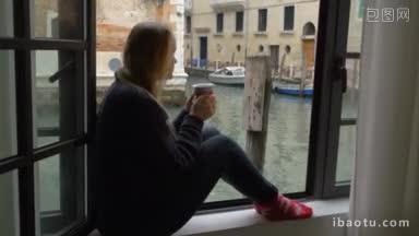 斯坦尼康拍摄的女人独自坐在窗台上的窗户是打开的，她看着威尼斯的景色，而有